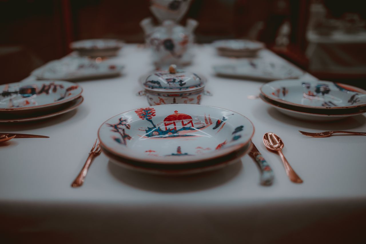 Close-up of a sophisticated porcelain place setting with intricate designs on a dining table.