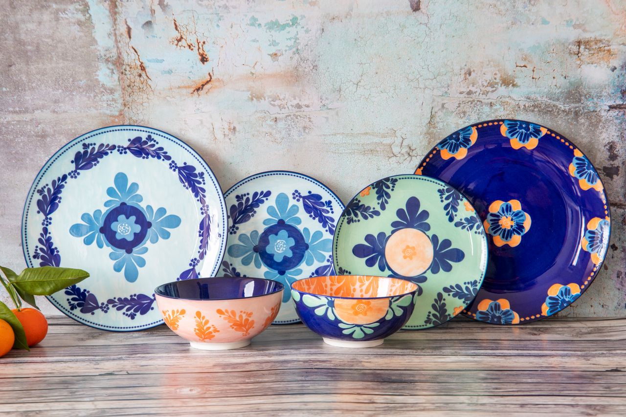 Vibrant ceramic plate and bowls set with floral patterns displayed on a rustic wooden table.