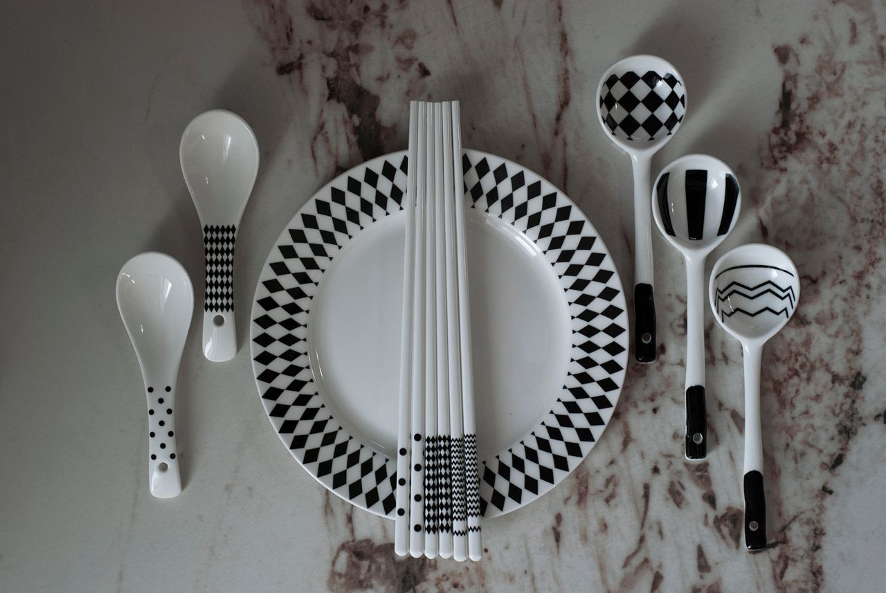 Elegant black and white tableware featuring geometric patterns displayed on a marble surface.