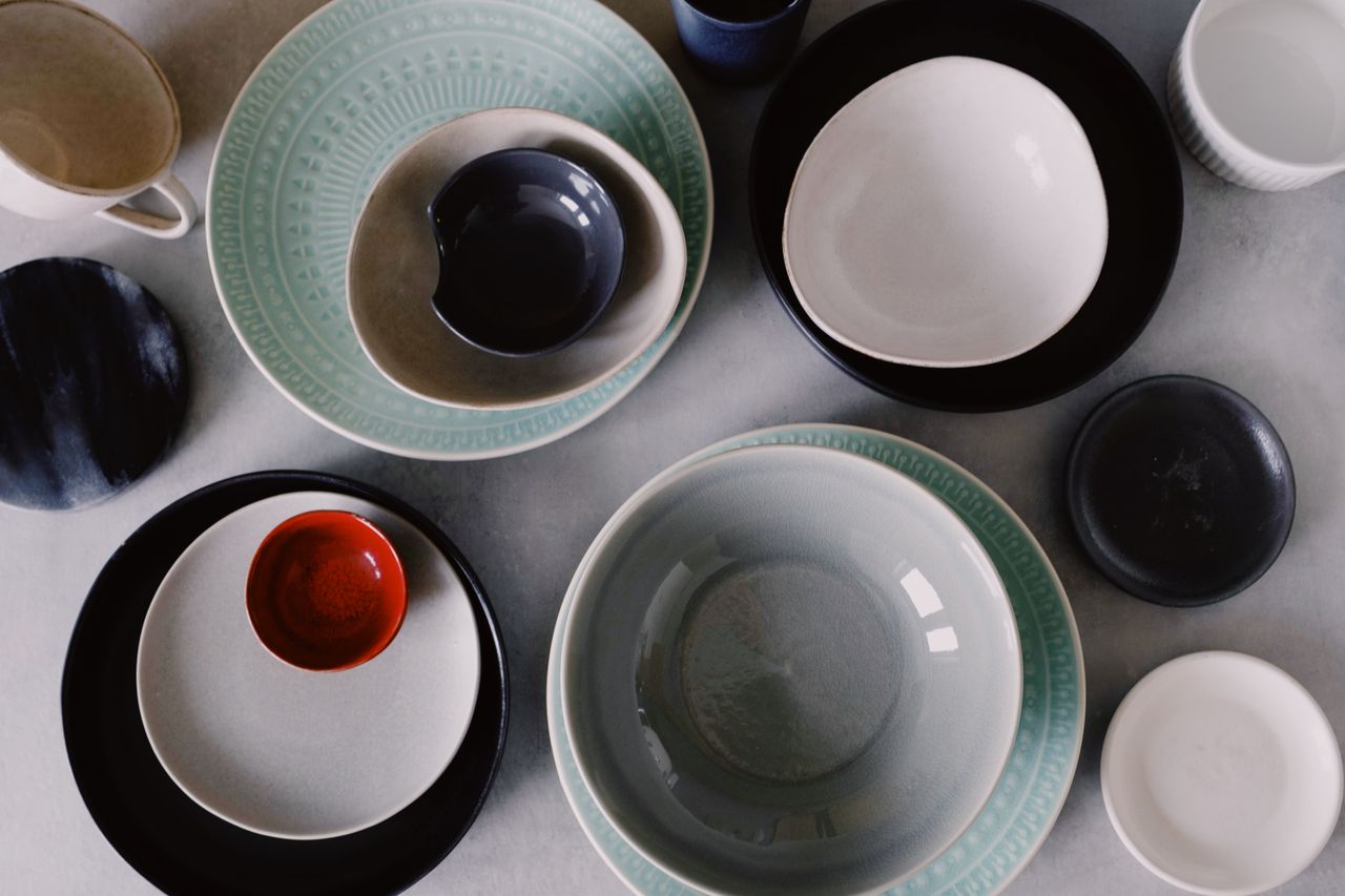 Top view of a variety of ceramic plates and bowls in an artistic arrangement showcasing modern tableware design.