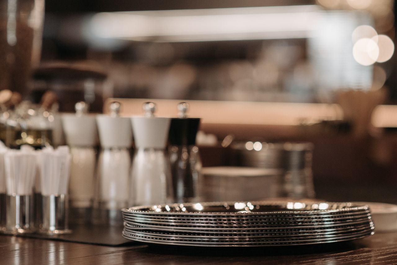 Close-up of shiny metal plates and condiments in a cozy restaurant setting.